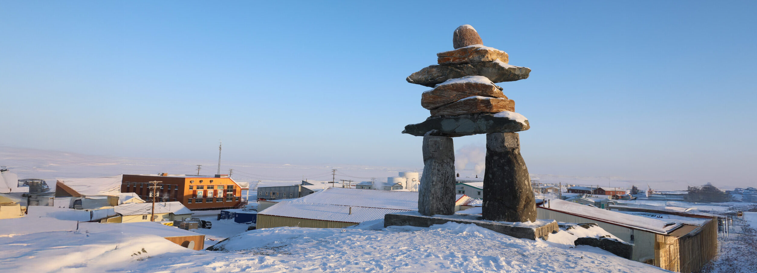 Single Inuksuk or Inukshuk landmark covered in snow on the top of the hill in the community of Rankin Inlet, Nunavut, Canada